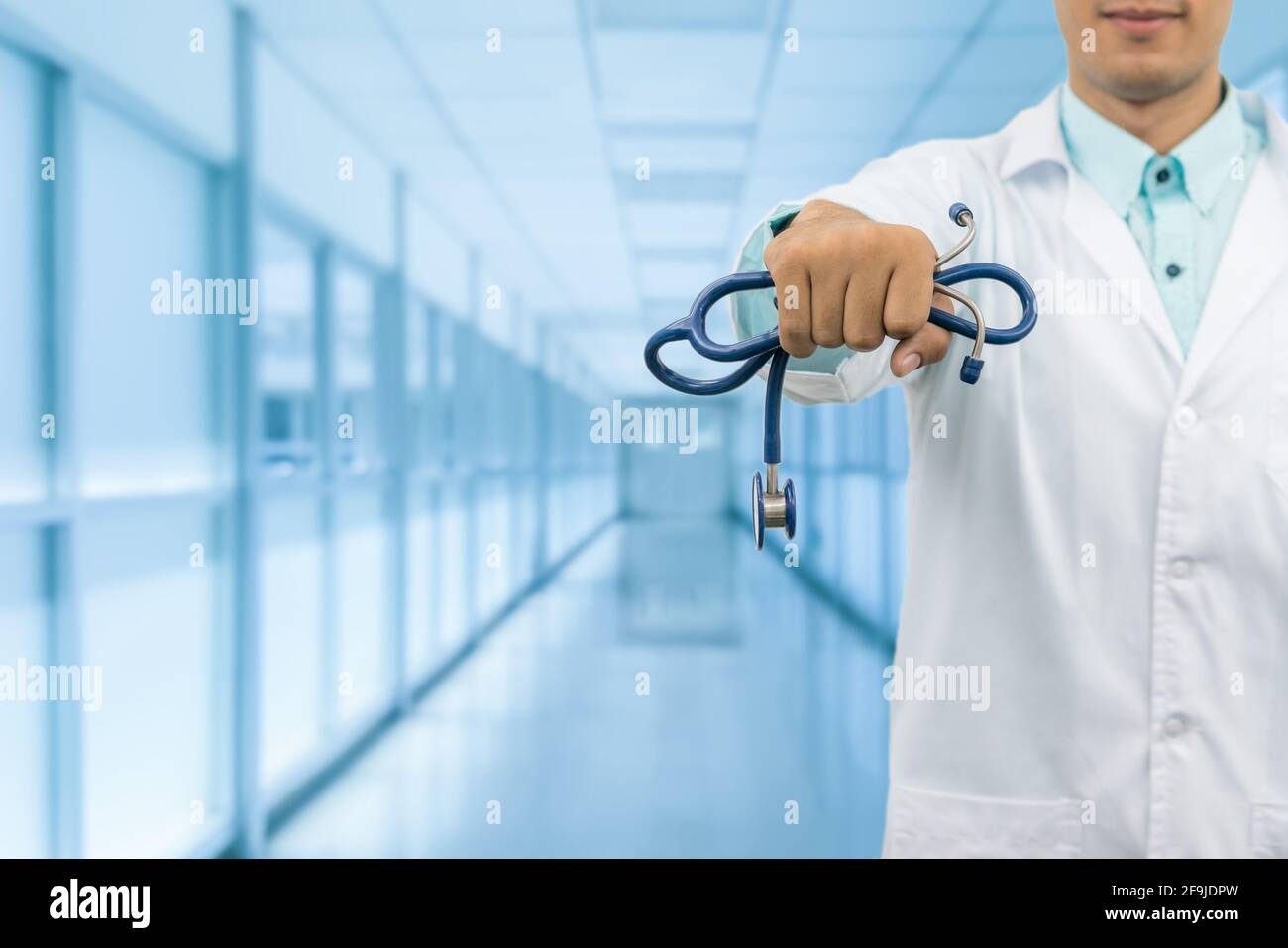Médecin homme tenant un stéthoscope, souriant sur le fond de l'hôpital. Service de santé, pratique générale et concept de carrière médicale. Banque D'Images