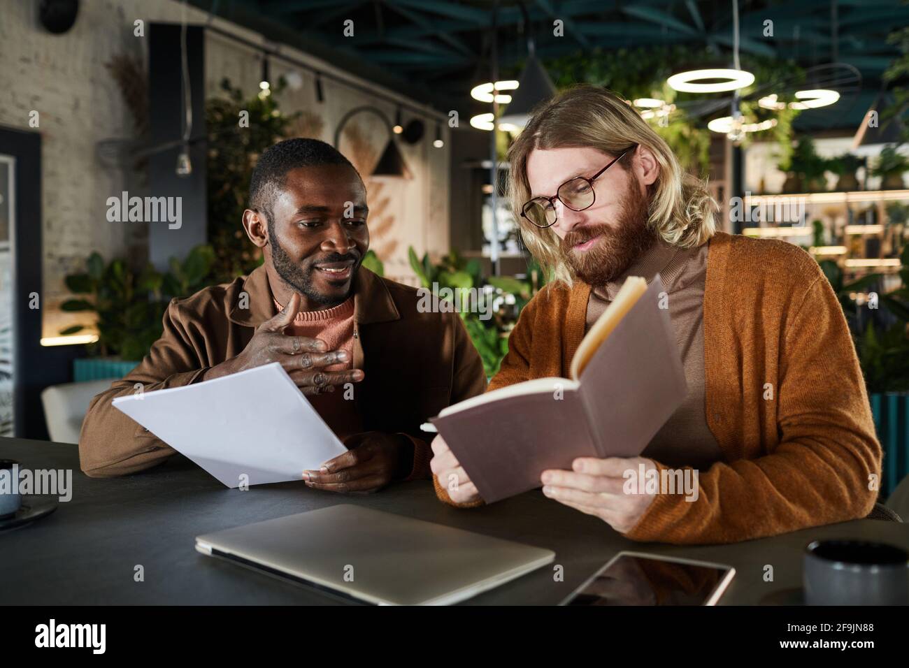 Portrait de deux hommes contemporains collaborant sur le projet lors d'une réunion d'affaires dans un bureau vert ou un café intérieur, espace de copie Banque D'Images