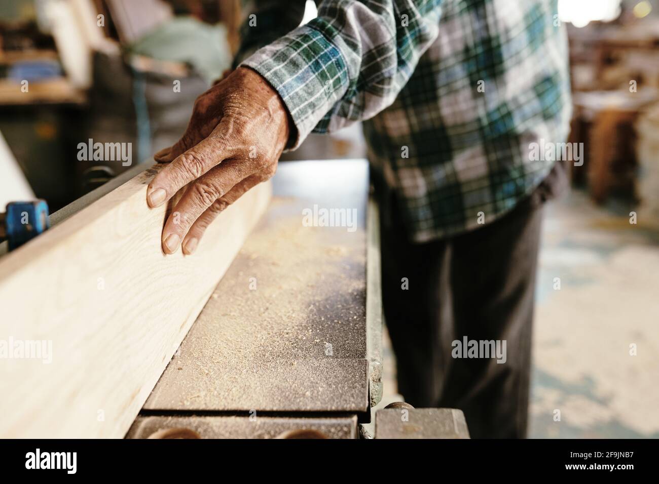 Image en gros plan du menuisier en utilisant la jointer de la paillasse à produire une surface plane le long des planches Banque D'Images