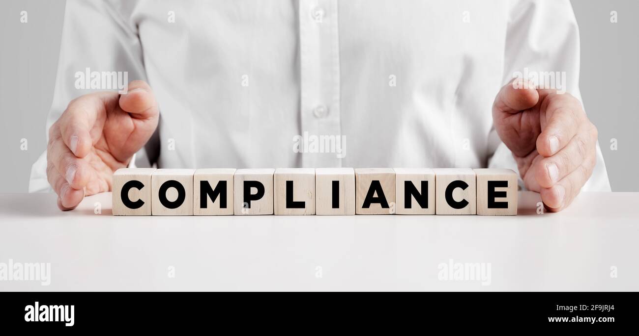 Mains d'homme d'affaires couvre les cubes en bois avec le mot conformité. Obéissance au concept de règles ou de normes. Banque D'Images
