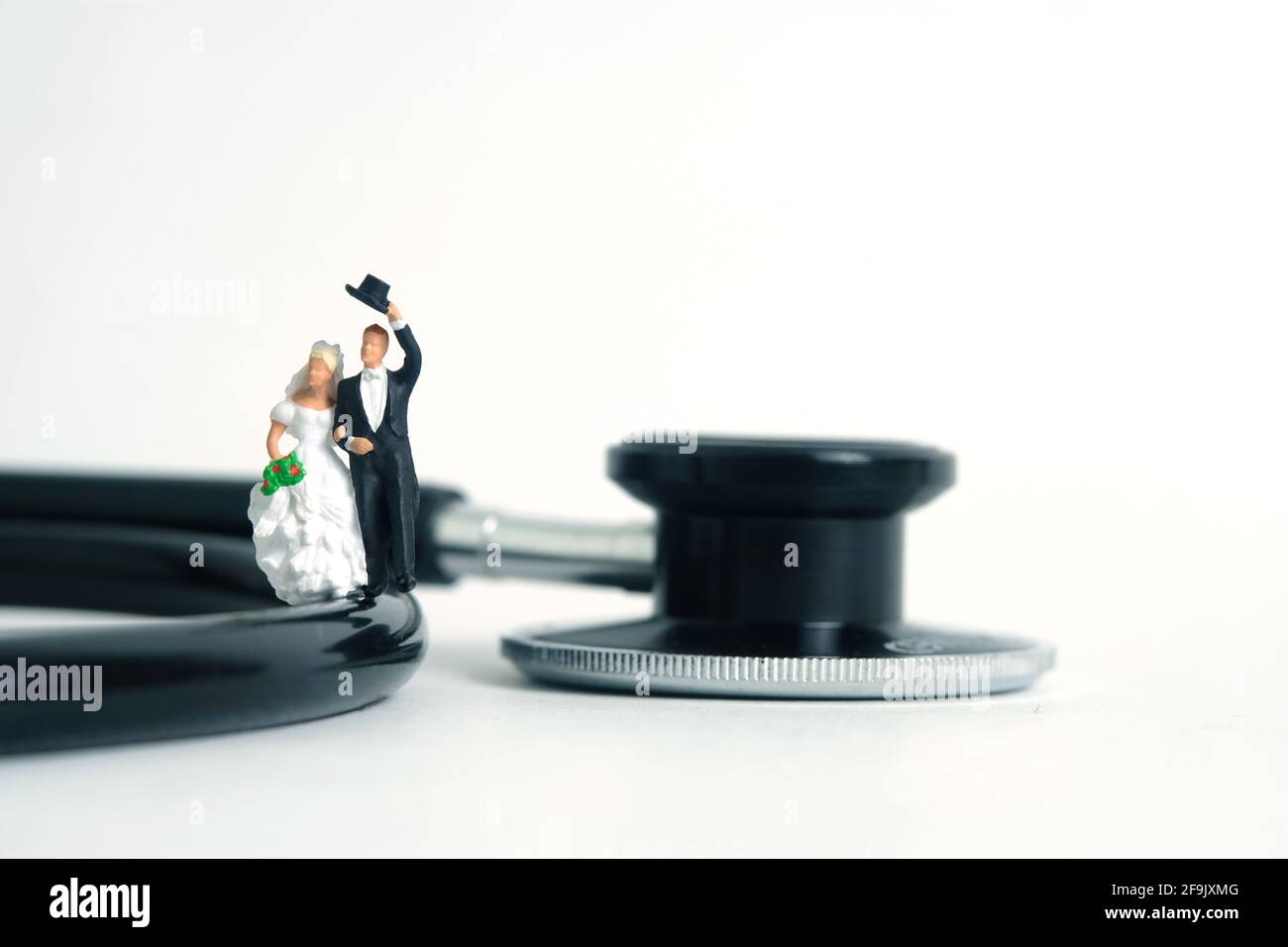 Mariage mariage mariage et couple examen médical concept miniature personnes jouet photographie. Mariée et marié avec stéthoscope isolé sur fond blanc. Banque D'Images