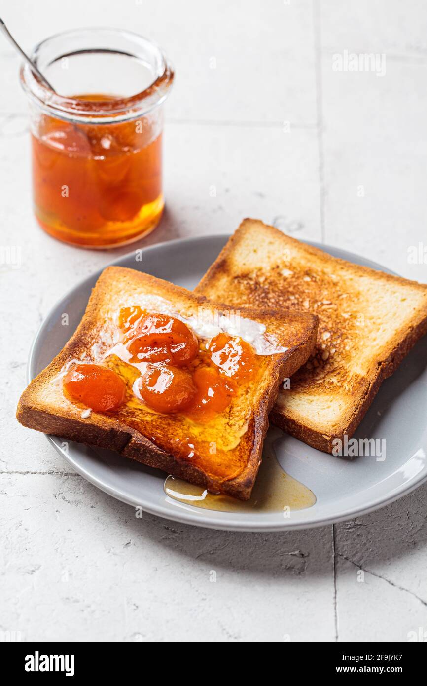Faire griller avec du beurre et de la confiture d'abricot sur une assiette grise. Concept de la nourriture pour le petit déjeuner. Banque D'Images