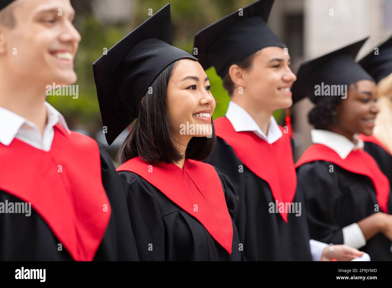 Groupe multiracial de diplômés ayant la cérémonie de remise des diplômes, clôture Banque D'Images