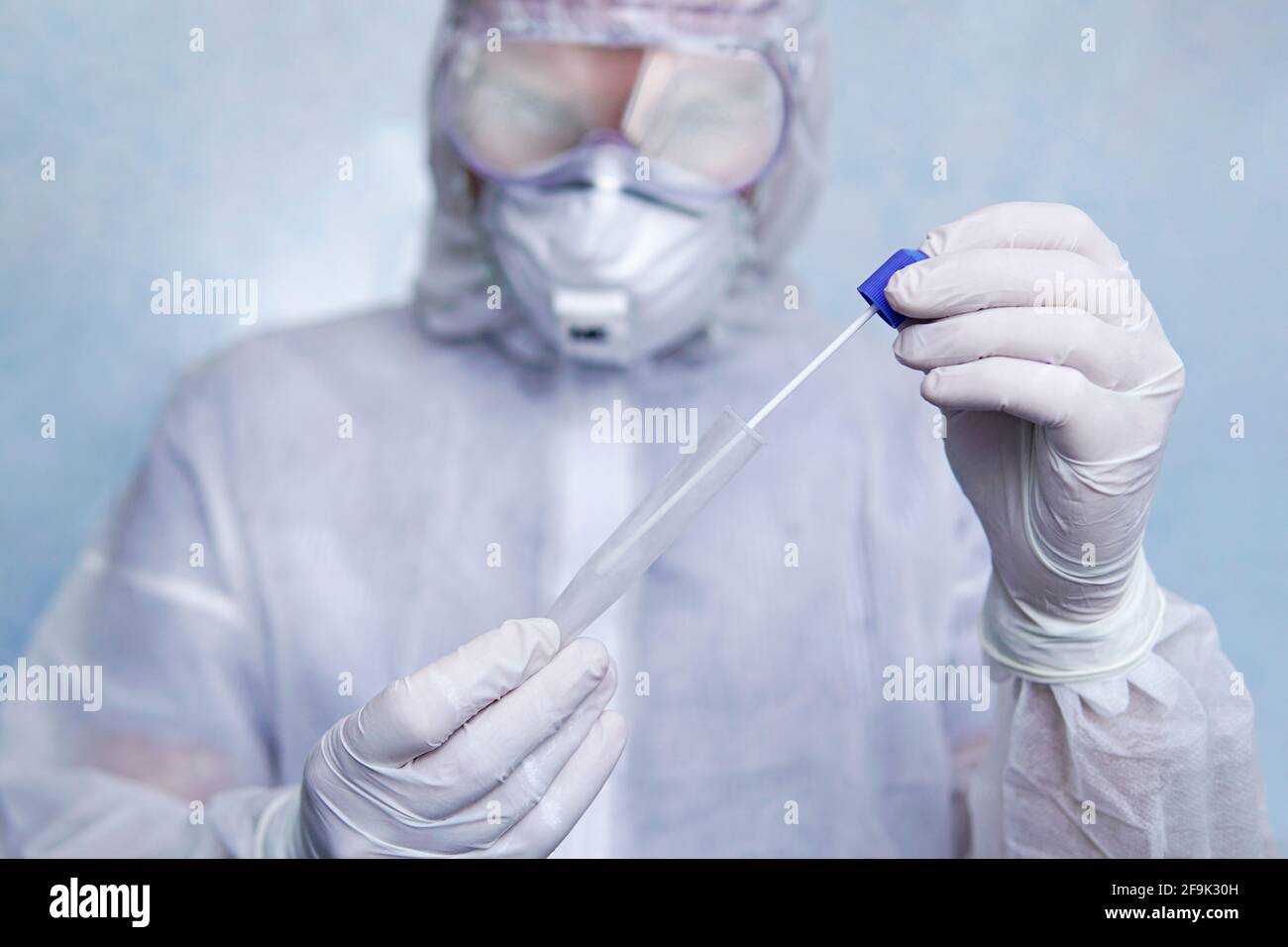 COVID-19. Écouvillon du coronavirus échantillon COVID-19. Test du coronavirus par écouvillon. Un homme en costume de protection chimique tient un tube à essai pour les analys Banque D'Images