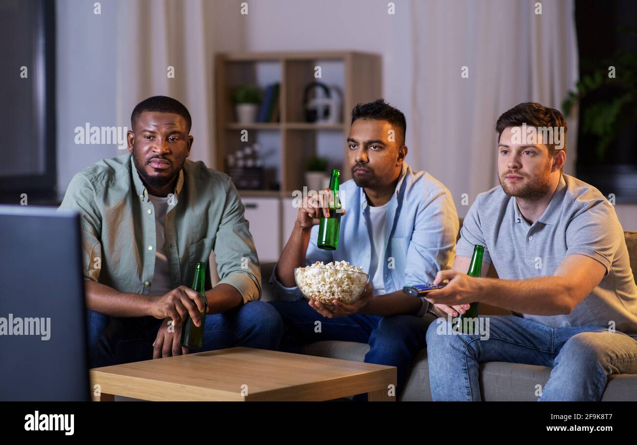 amis masculins avec bière regardant la télévision à la maison Banque D'Images