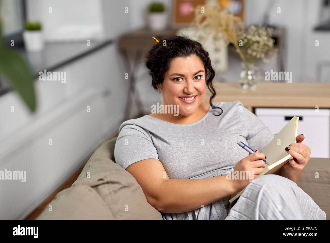 jeune femme heureuse avec journal sur le canapé à la maison Banque D'Images