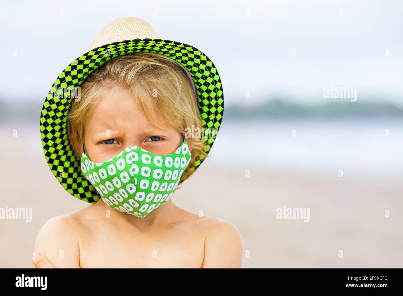 Enfant en chapeau de paille, les masques élégants s'amusent sur la plage.  Nouvelles règles pour porter un masque de couverture en tissu dans les  lieux publics en raison de coronavirus COVID Photo