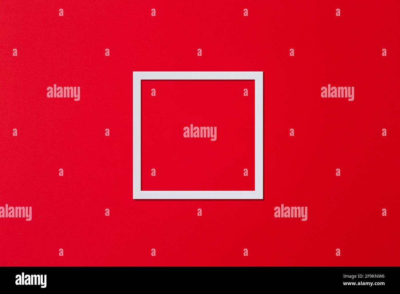 Cadre blanc sous forme de carré sur fond rouge, minimalisme. Flat lay, espace de copie. Banque D'Images
