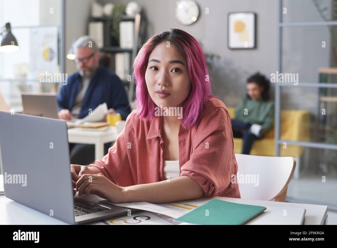 Portrait de la jeune femme asiatique assis à la table et taper sur un ordinateur portable au bureau Banque D'Images