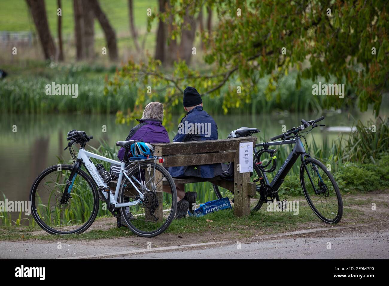 Un couple s'assoit sur un banc à côté de l'étang dans le village de Buriton, à trois miles au sud de Petersfield, Hampshire Angleterre Banque D'Images