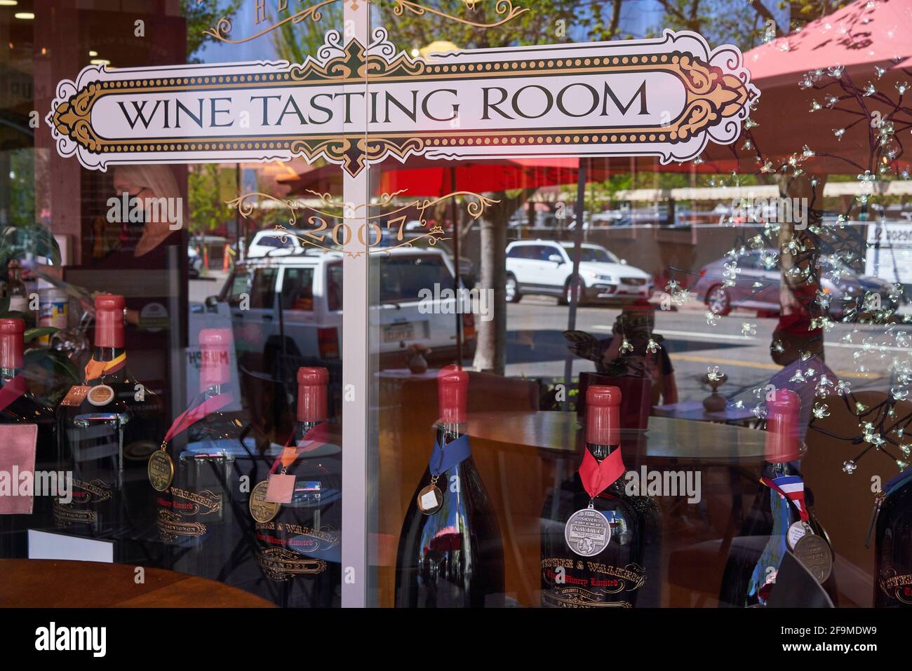 Étiquette de la salle de dégustation de vin et bouteilles de vin affichées sur une fenêtre, réflexions de la rue et deux personnes assises à une table à Healdsburg, Californie. Banque D'Images