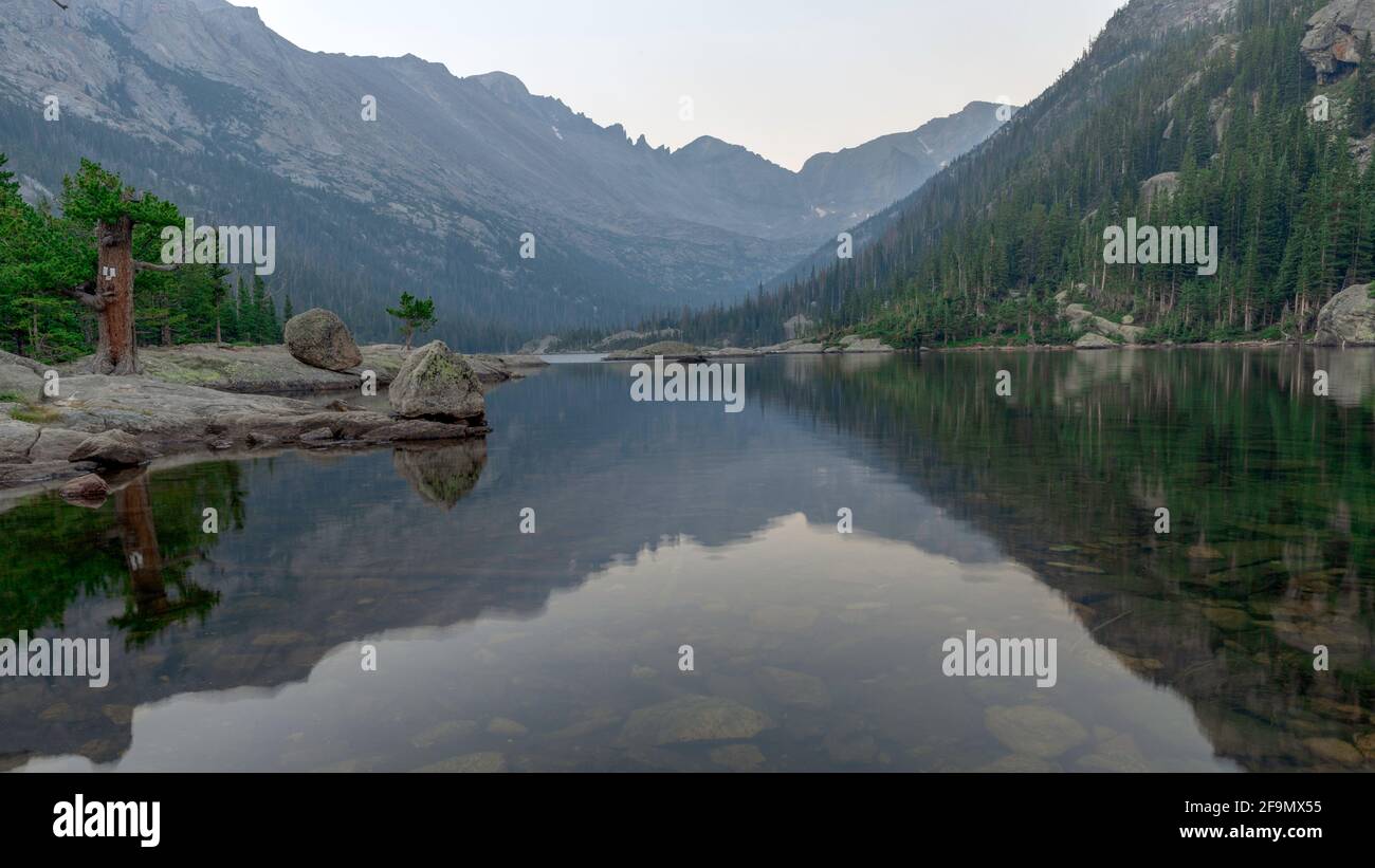 La brume fumée d'un feu de forêt à proximité se diffuse Le lever du soleil au-dessus du lac Mills Banque D'Images