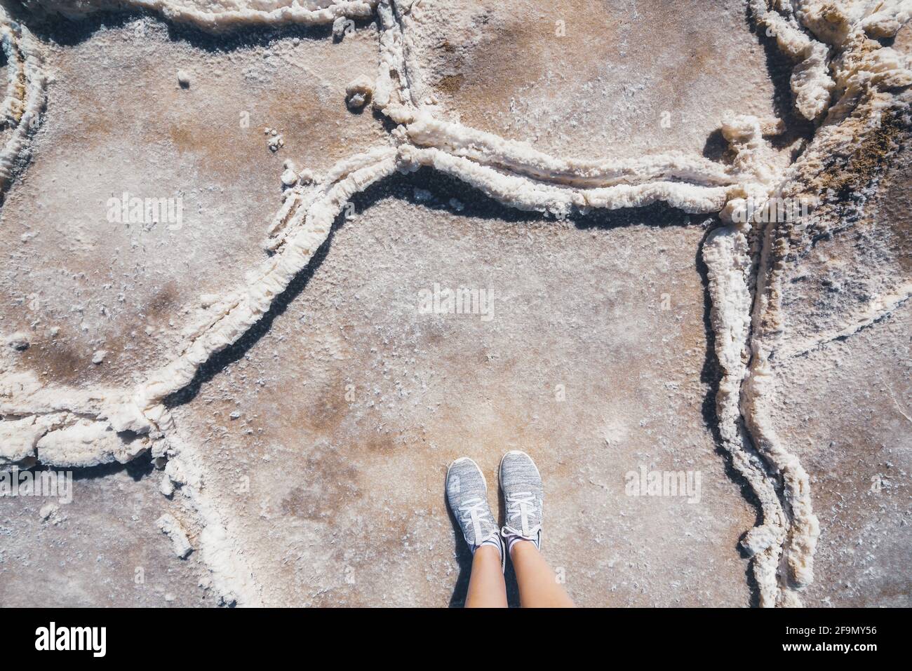 Une femme se tient debout sur des plateaux de sel dans le parc national de la Vallée de la mort. Vue du dessus du point de vue personnel. Salez les plats, texture gros plan Banque D'Images