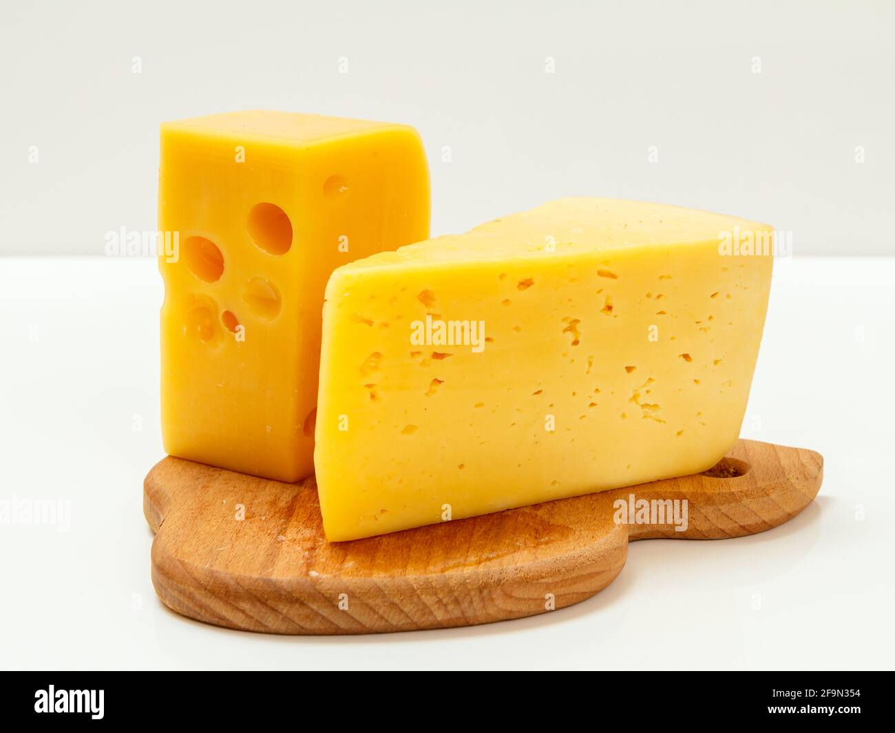 Fromage sur planche à découper en bois avec fond blanc Banque D'Images