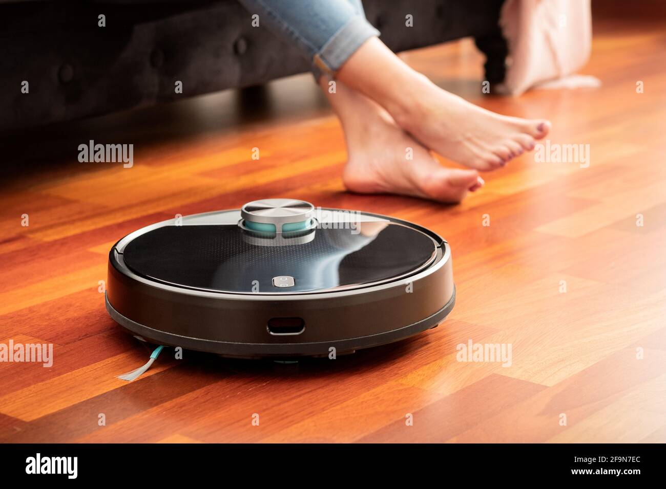 Les pieds des jeunes filles lorsqu'un aspirateur automatique rond et  intelligent passe pour nettoyer le sol, contrôlant la machine robot ménager  Photo Stock - Alamy