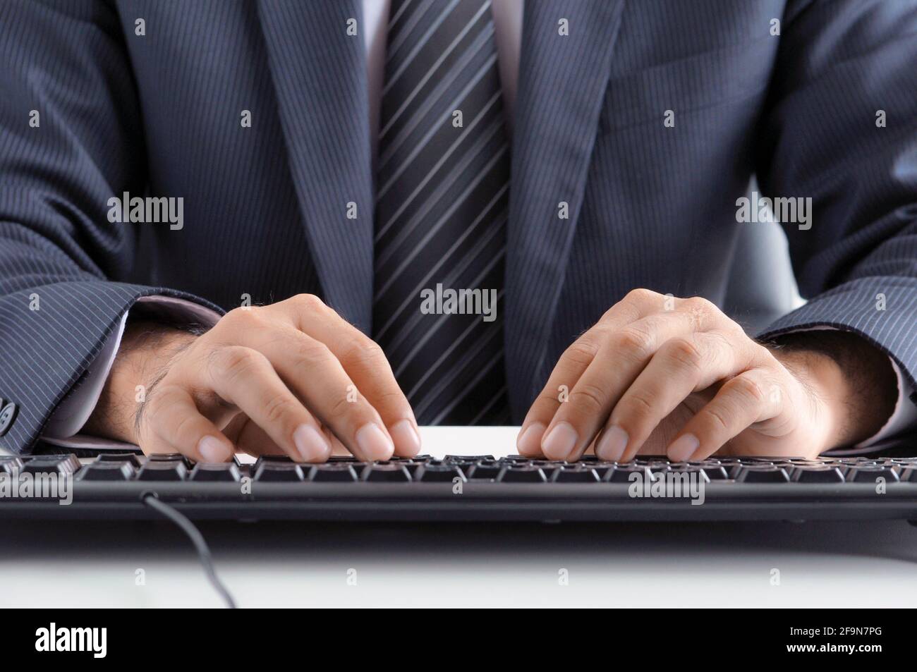 Homme d'affaires mains dactylographiant clavier d'ordinateur Banque D'Images