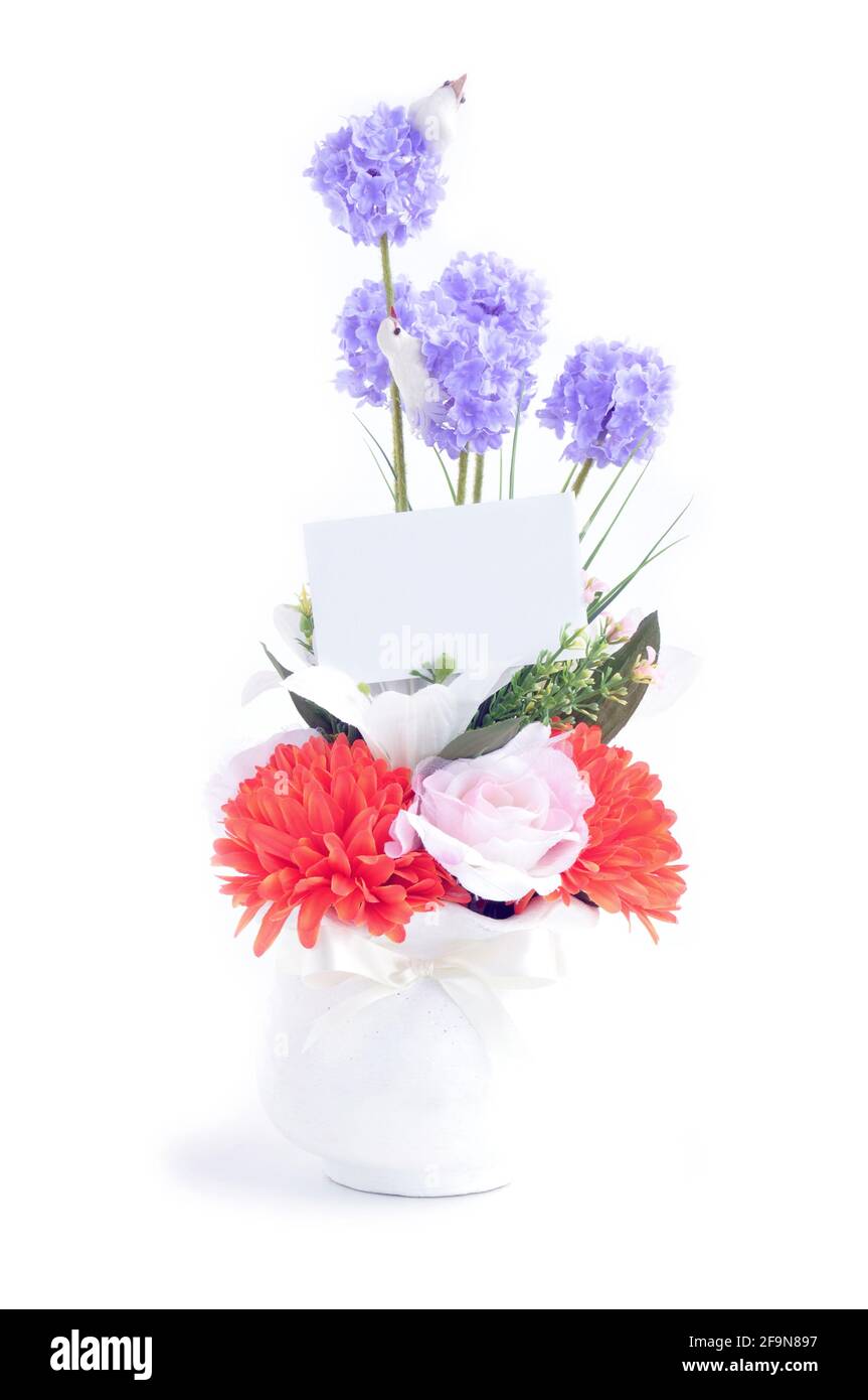 Bouquet de fleurs artificielles dans vase blanc avec carte vide - isolé Banque D'Images
