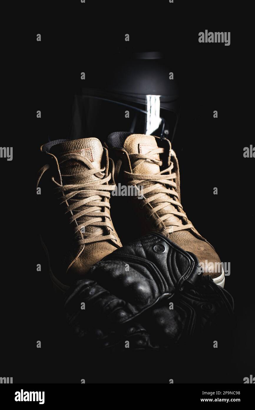 Accessoires de sécurité pour moto. Gants, casque et chaussures en cuir sur fond noir. Banque D'Images