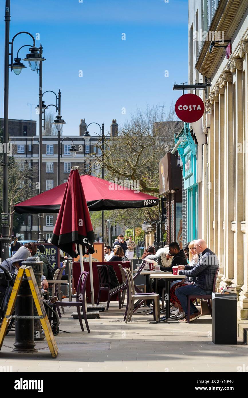 Café populaire servant les clients assis à l'extérieur sous un soleil de printemps chaud Banque D'Images