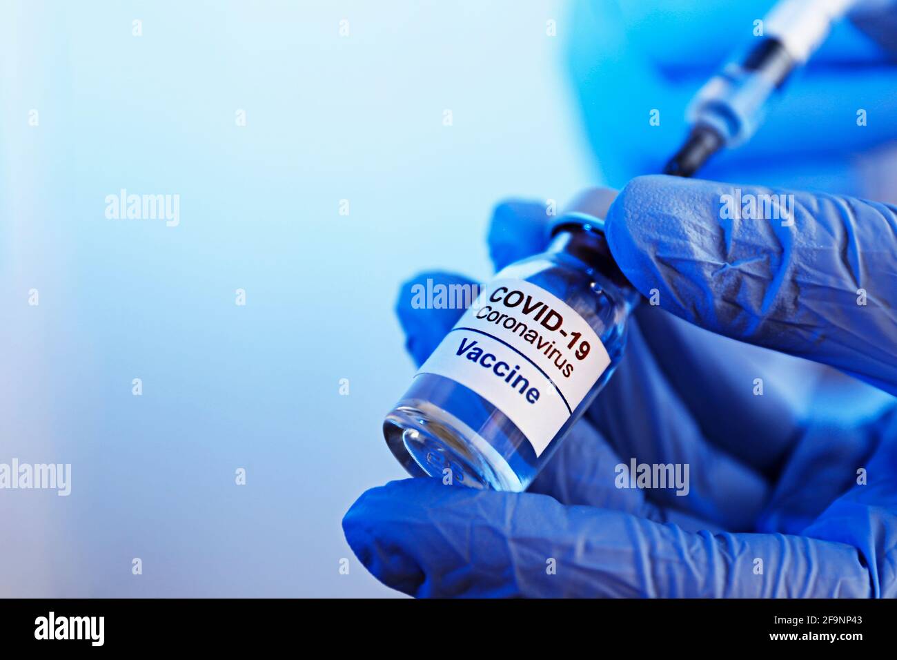 Gros plan des mains du médecin dans des gants en latex remplissant la seringue avec le nouveau vaccin Covid-19 du flacon. Gros plan, espace de copie, arrière-plan. Banque D'Images