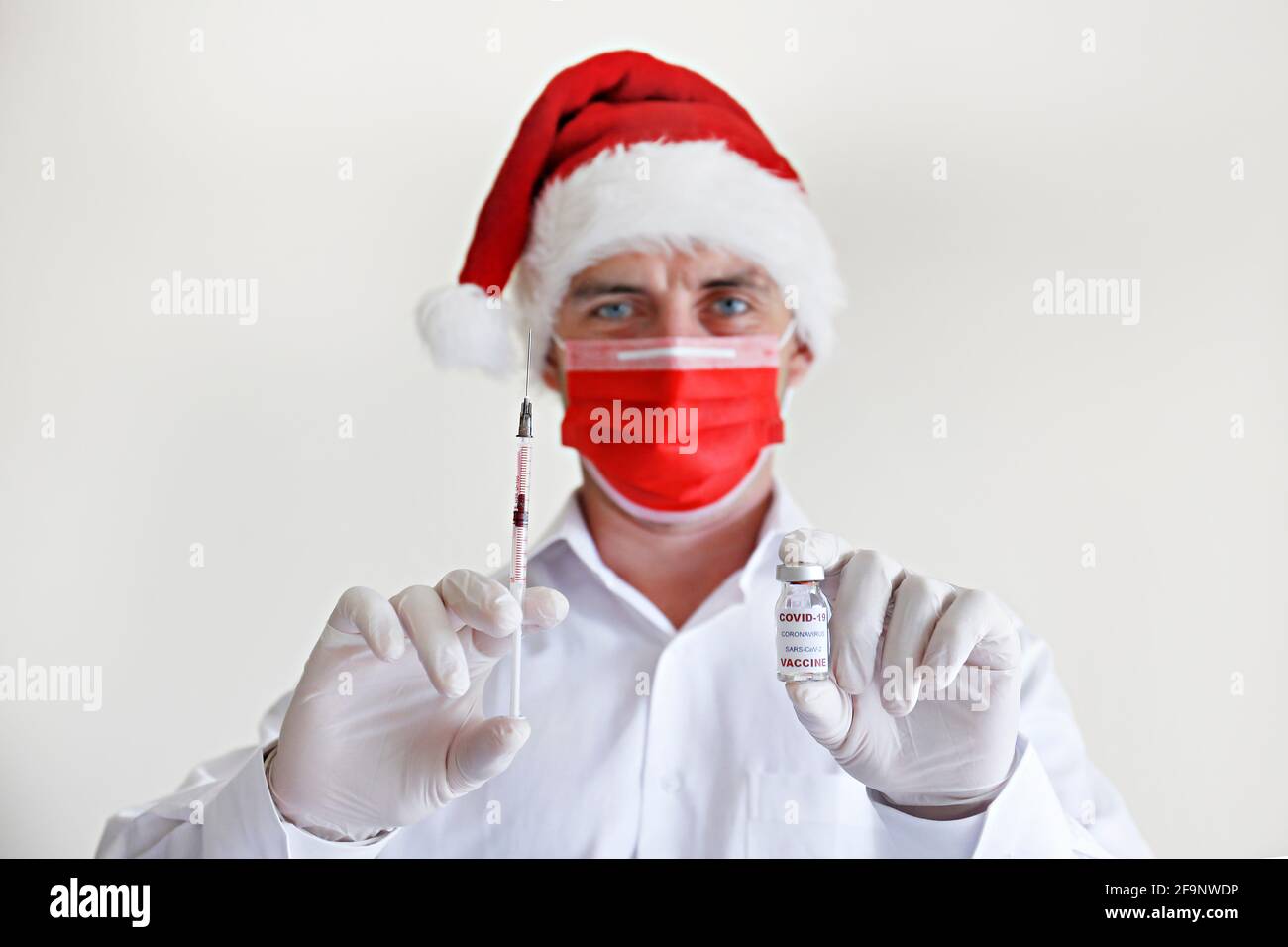 Le vaccin coronavirus comme le concept de noël présent. Portrait d'un  médecin portant le chapeau du Père Noël, un masque rouge et des gants en  latex démontrant le nouveau Covid-19 Photo Stock -