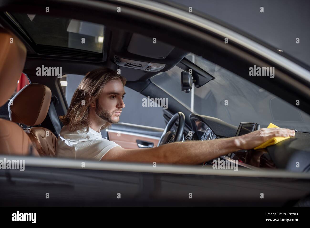 Homme assis dans le tableau de bord d'essuyage de voiture Banque D'Images