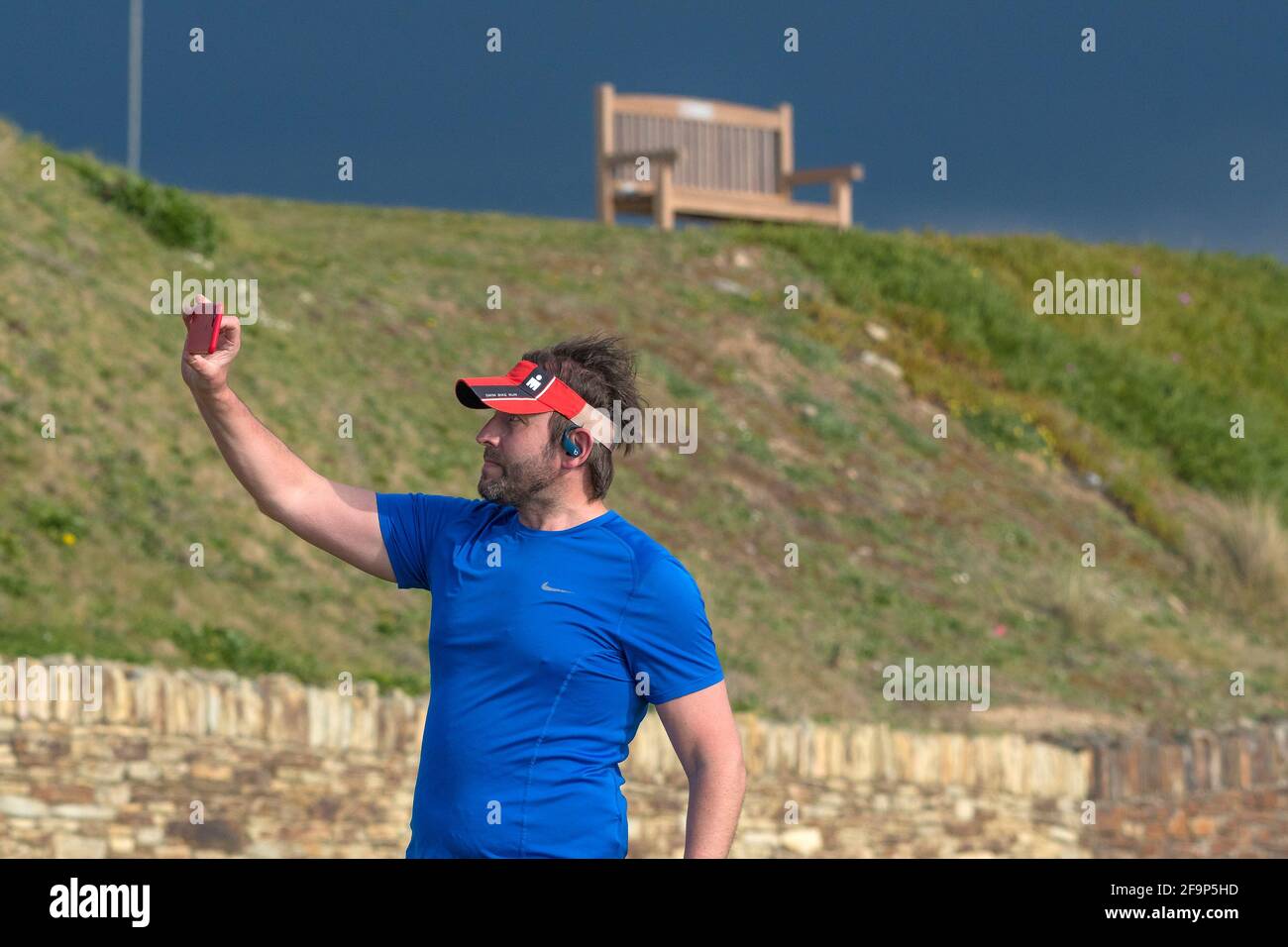 Un vacanciers portant un pare-soleil à l'aide d'un smartphone pour prendre une photo de selfie en vacances à Newquay, en Cornouailles. Banque D'Images