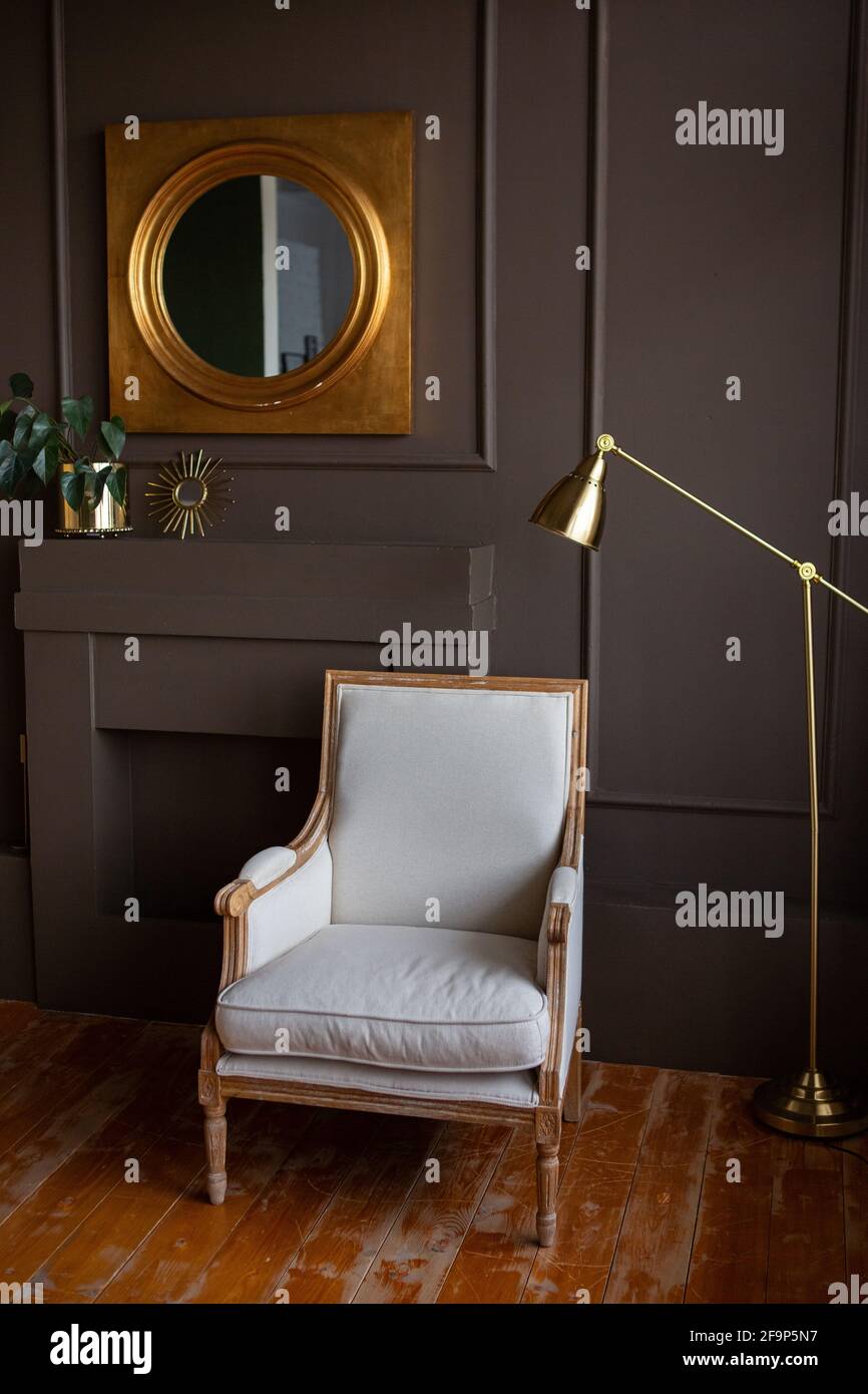 Chaise grise élégante contre un mur gris foncé.Intérieur de salon tendance, à côté d'une lampe et d'un miroir. Banque D'Images