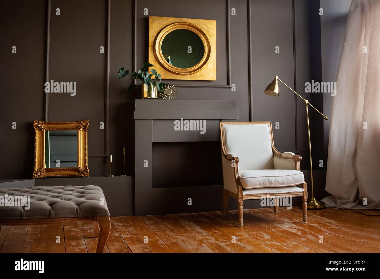 Chaise grise élégante contre un mur gris foncé.Intérieur de salon tendance, à côté d'une lampe et d'un miroir. Banque D'Images