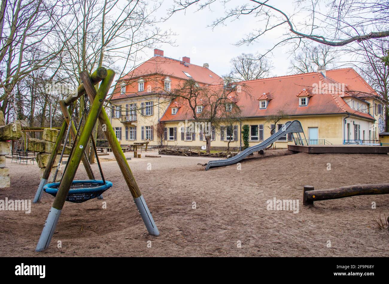 détail d'un terrain de jeu avec une balançoire et bâtiment jaune derrière elle à potsdam, allemagne. Banque D'Images