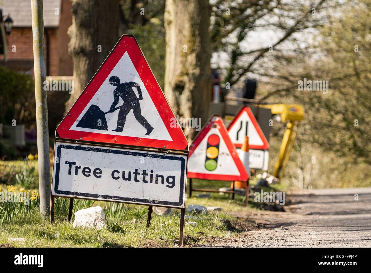 Panneau d'avertissement rouge et blanc pour couper les arbres sur le côté de la route avec le symbole représentant un travailleur de la route. Panneau de signalisation signalant un danger aux conducteurs. Banque D'Images