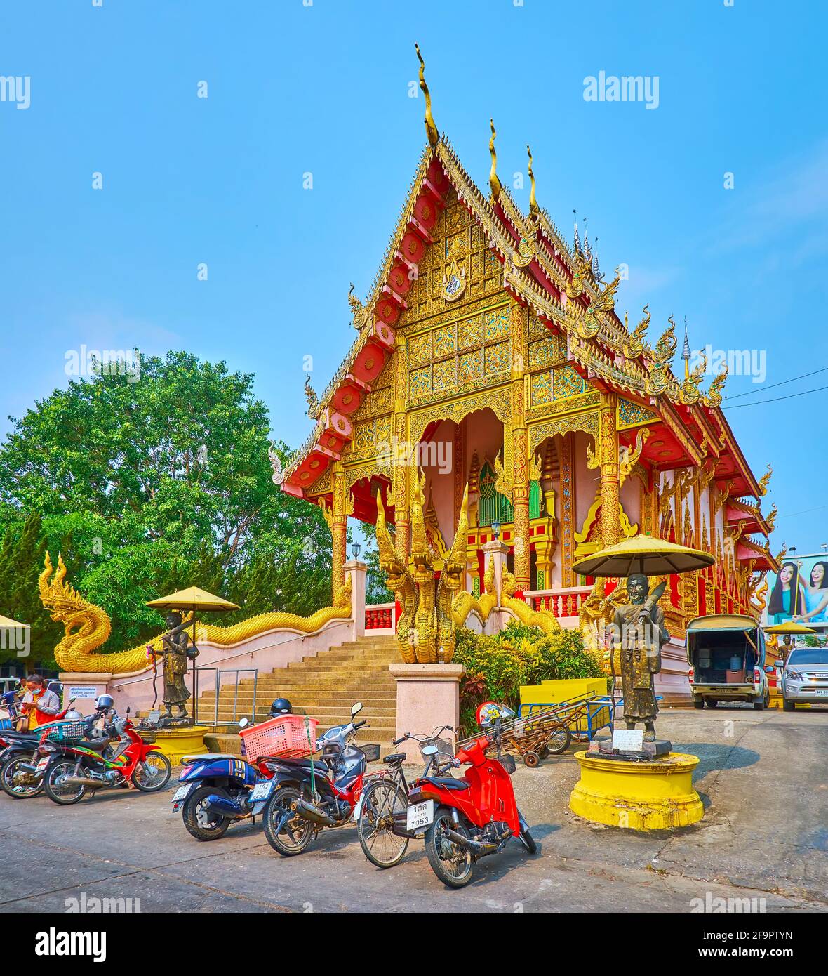 La façade pittoresque du temple médiéval Wat Mung Muang avec des sculptures de serpents géants de Naga, des motifs de dorures sculptés, des colonnes, un bargeboard complexe Banque D'Images