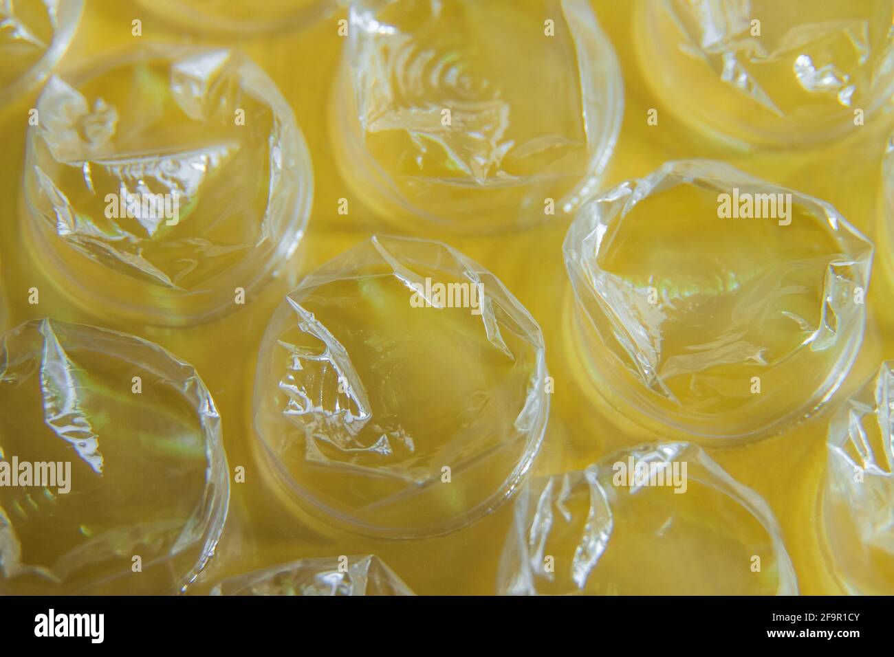 Macro-photographie de film à bulles d'air en plastique sur fond jaune. Banque D'Images