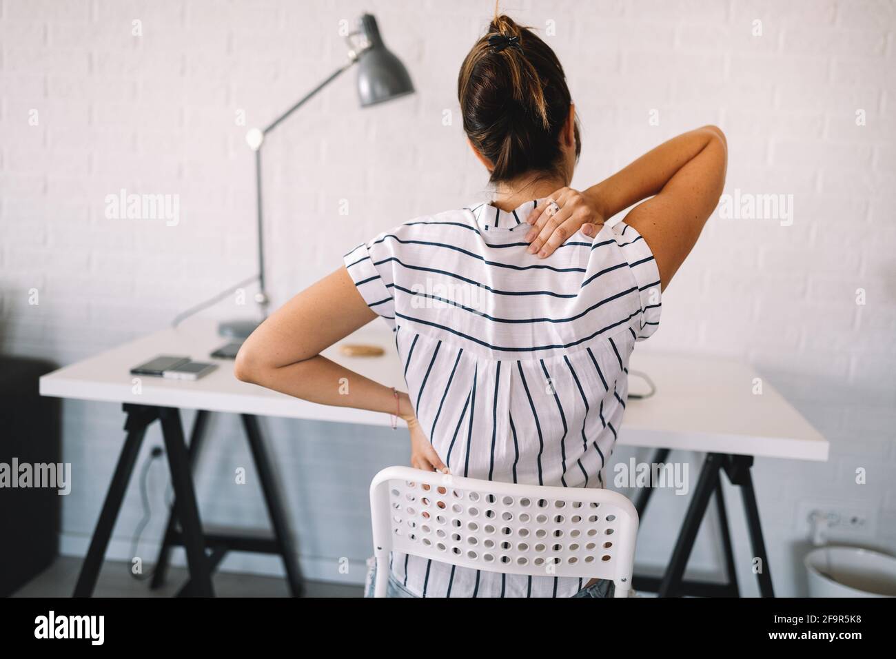 Femme surchargés d'une douleur dans la région de bureau avec une mauvaise posture Banque D'Images