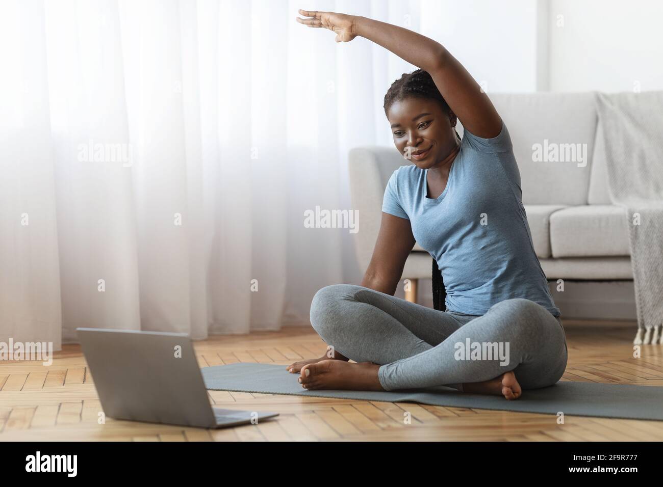 Fitness en ligne. Entraînement souriant de la Black Lady devant l'ordinateur portable à la maison Banque D'Images