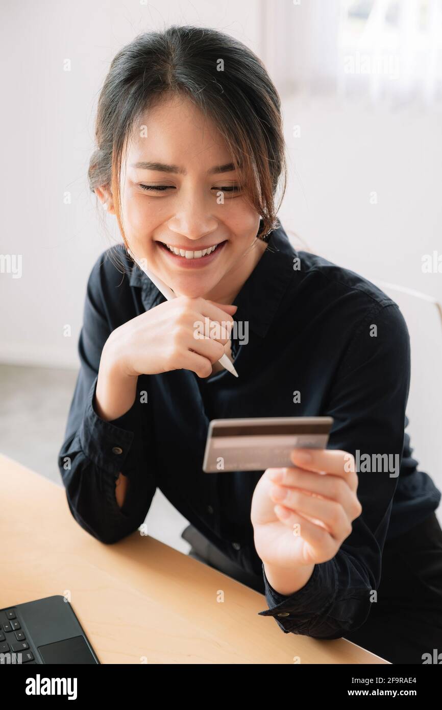 Femme gaie souriant et tenant la carte de crédit pour le paiement en ligne Banque D'Images