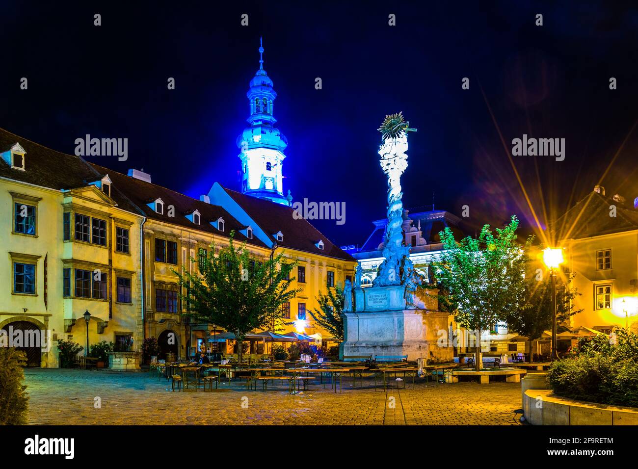 Vue nocturne de la place principale éclairée Dans la ville hongroise Sopron y compris la colonne Sainte trinité et la célèbre cheminée Banque D'Images