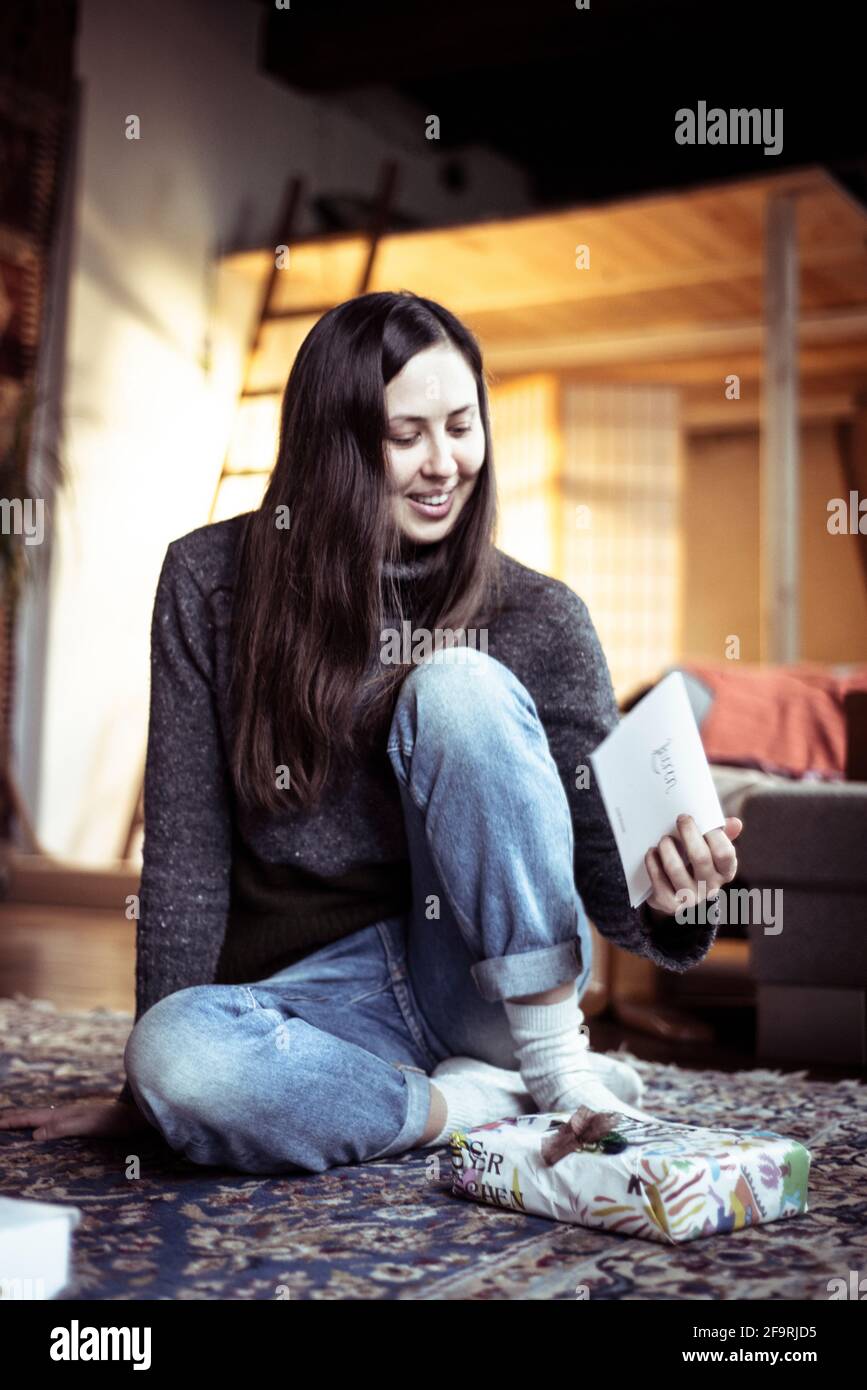 Jeune femme sourit à la carte pour la célébration de noël dans la maison confortable Banque D'Images