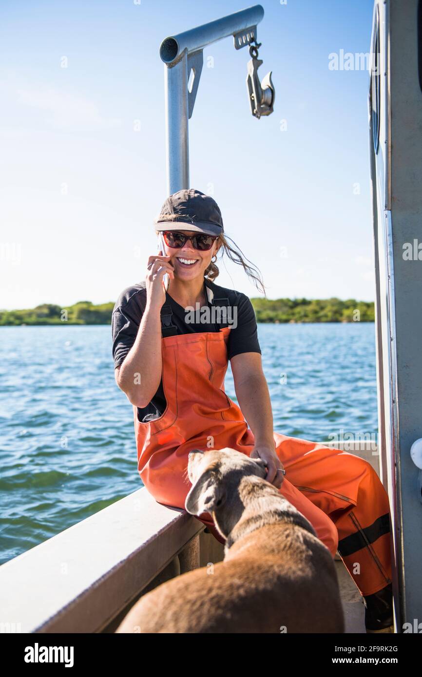 Femme au téléphone en travaillant sur l'eau en aquaculture ferme ostréicole Banque D'Images