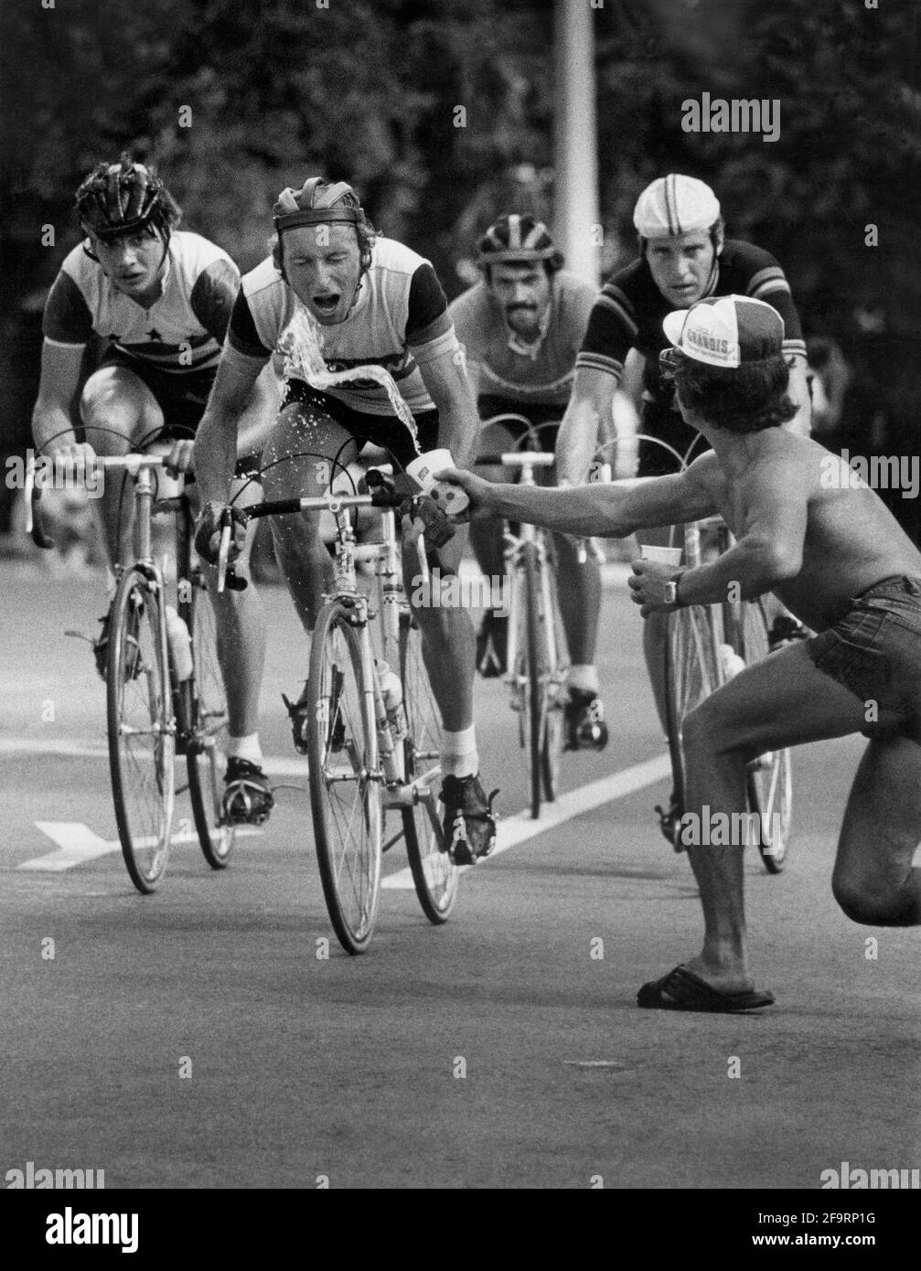 Le coureur cycliste reçoit de l'eau dans sa bouche lors d'une course dans le sud de la Floride, ca. années 1960. Banque D'Images