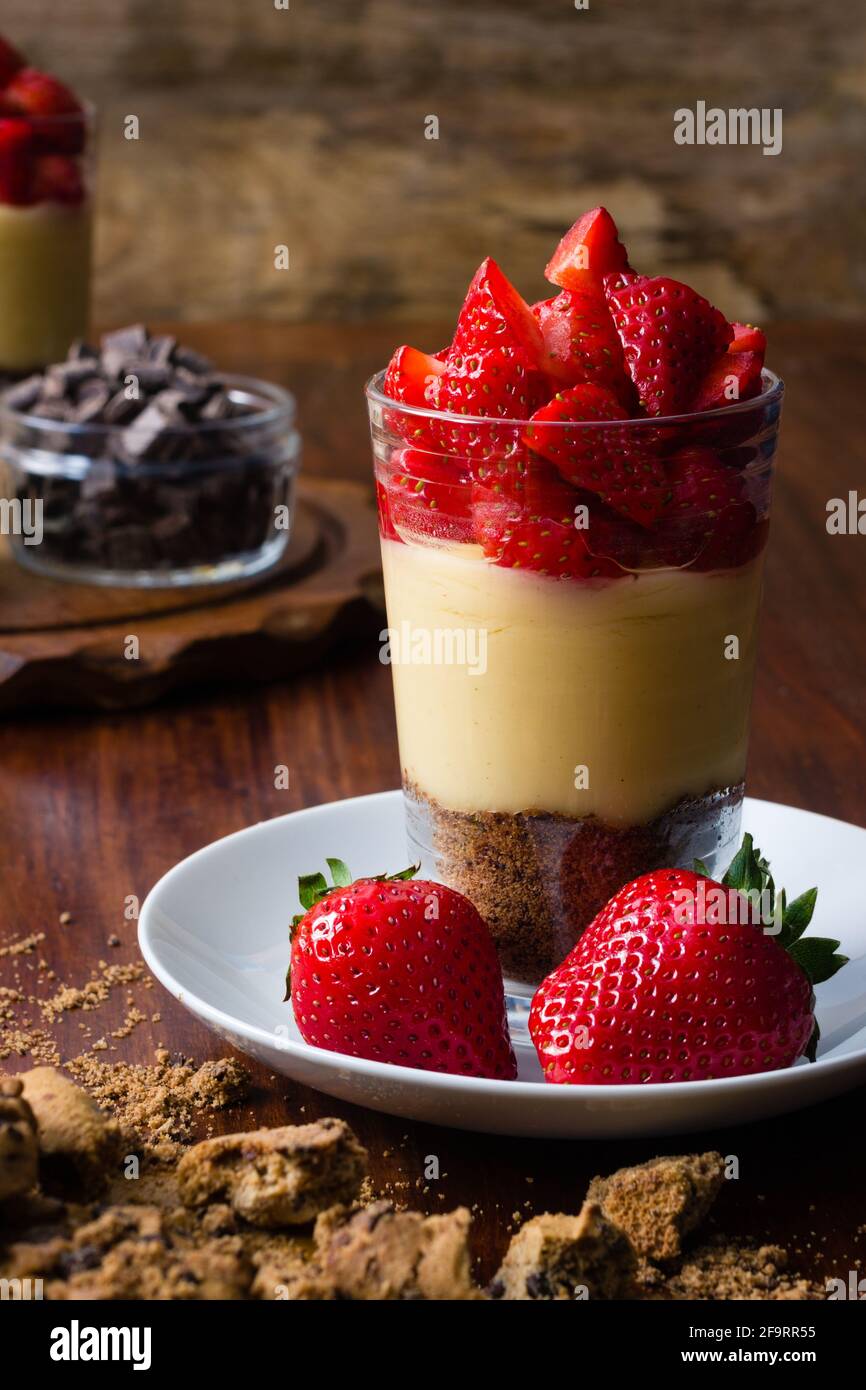 Dessert aux fraises douces en verre avec pudding et biscuits sur fond en bois Banque D'Images