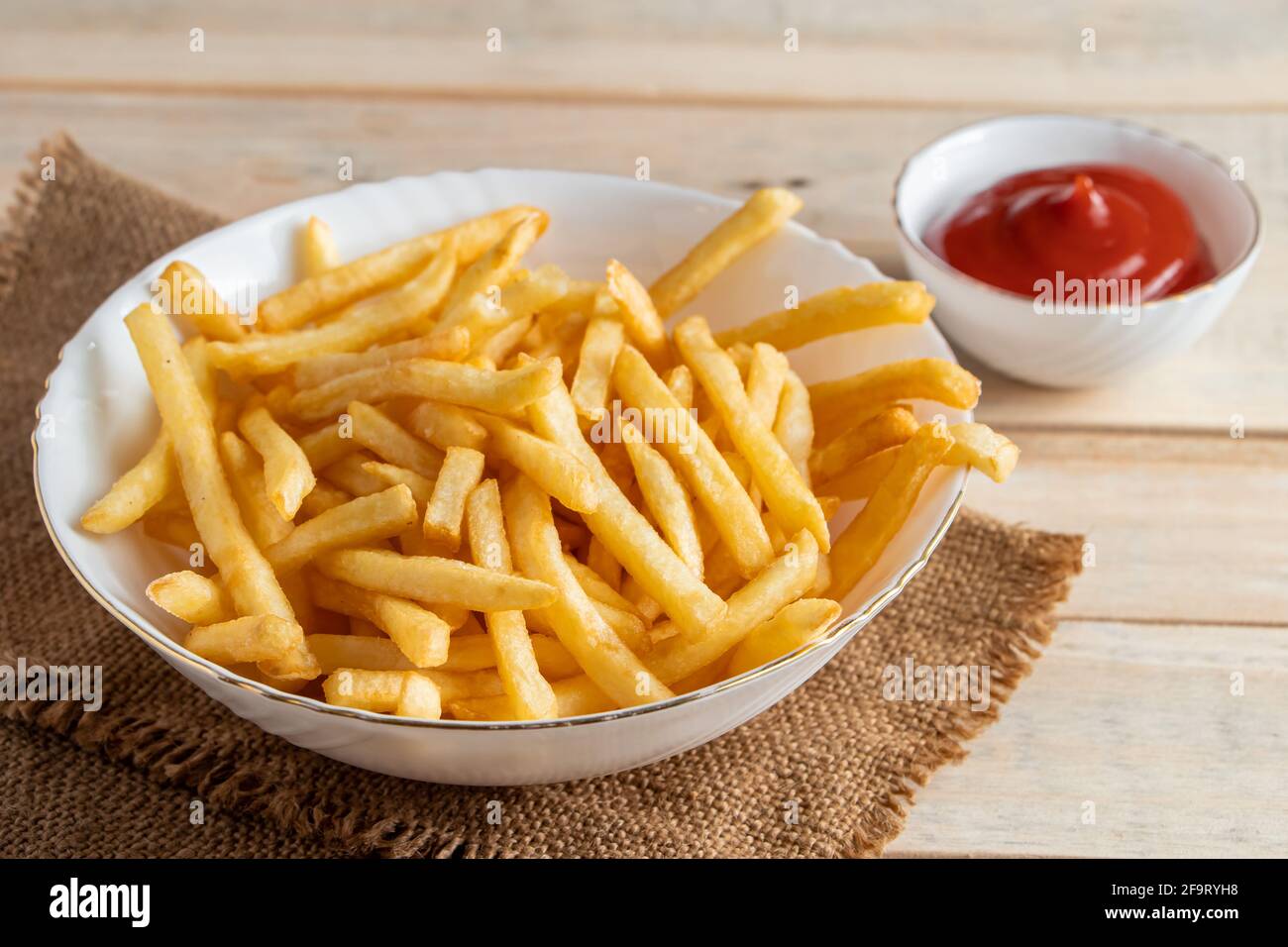 Frites dorées chaudes avec ketchup sur fond de bois. Restauration rapide américaine savoureuse. Banque D'Images