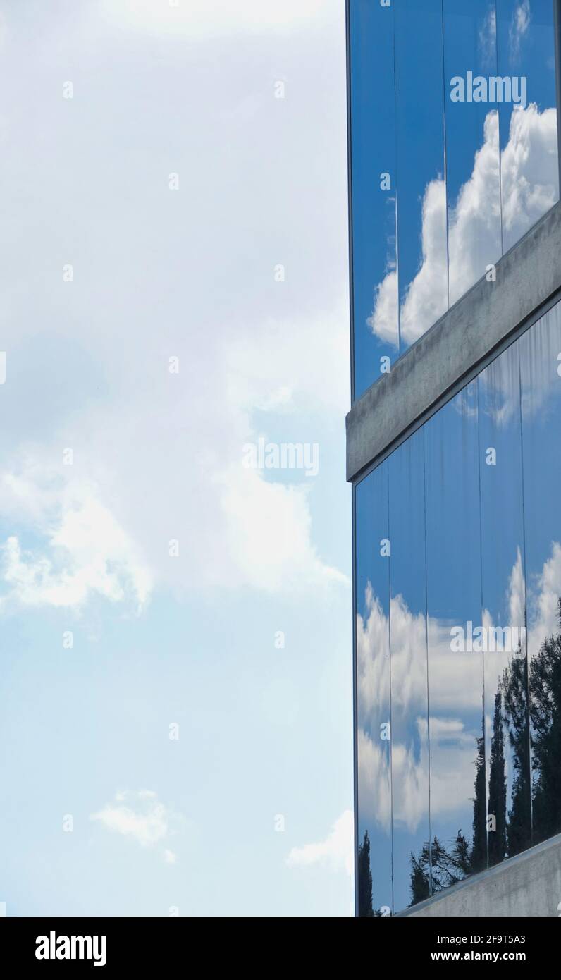Ciel bleu avec nuages reflétés dans la façade en verre de un bâtiment Banque D'Images