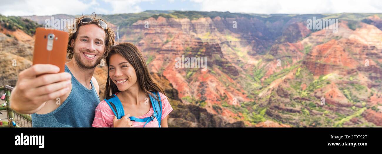 Un couple d'Hawaï prenant un selfie au Waimea Canyon Kauai. Les randonneurs à la randonnée guetteur Voyage les touristes prenant la photo de téléphone mobile. Vacances d'été Banque D'Images