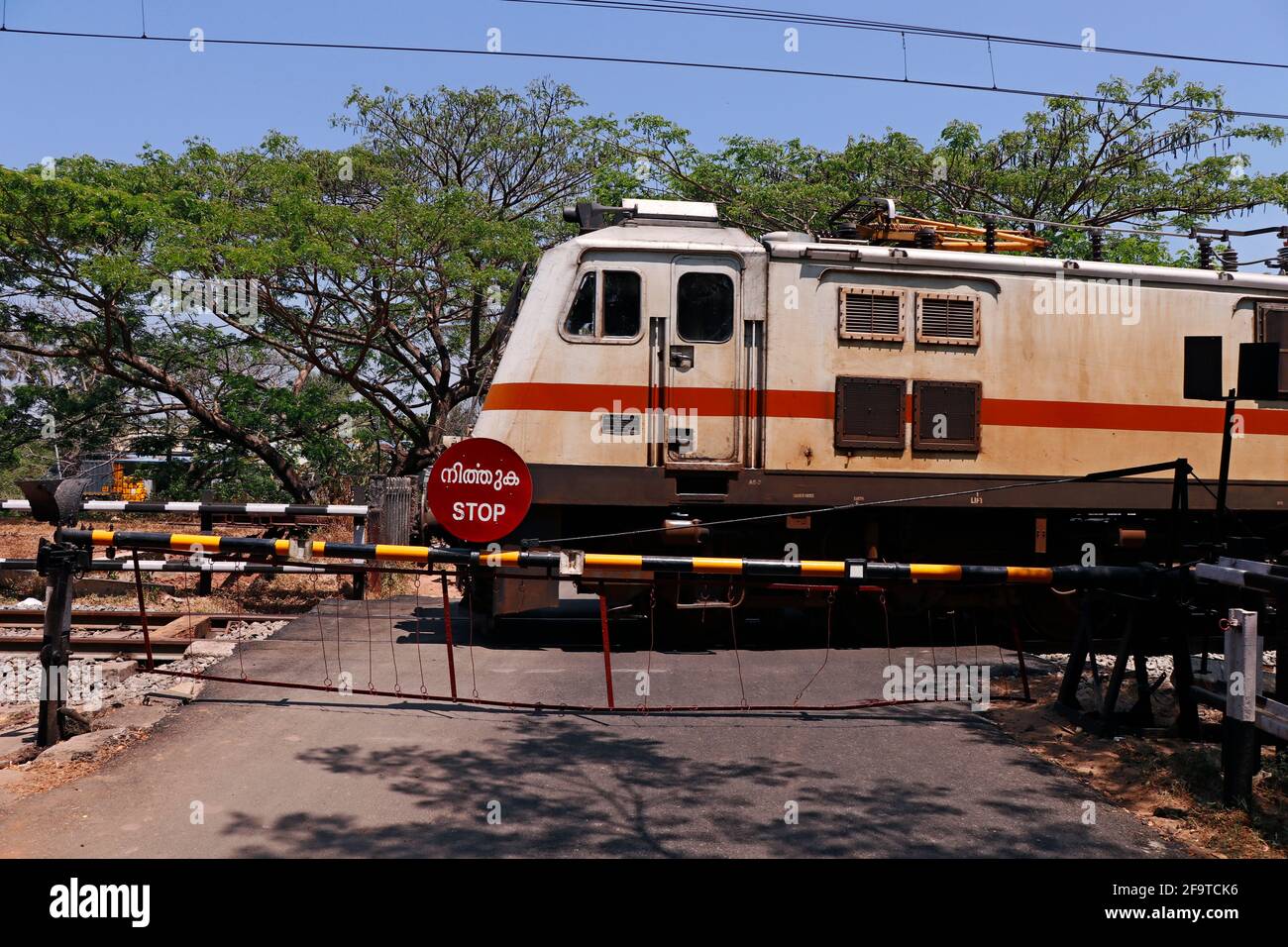 Kochi, Kerala, Inde -le 5 mars 2021 un train se déplaçant avec un support électrique à travers la croix de niveau de chemin de fer indienne Banque D'Images