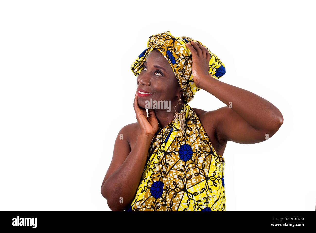 jeune femme africaine debout dans un chiffon dans un studio et regardant là-haut en souriant. Banque D'Images