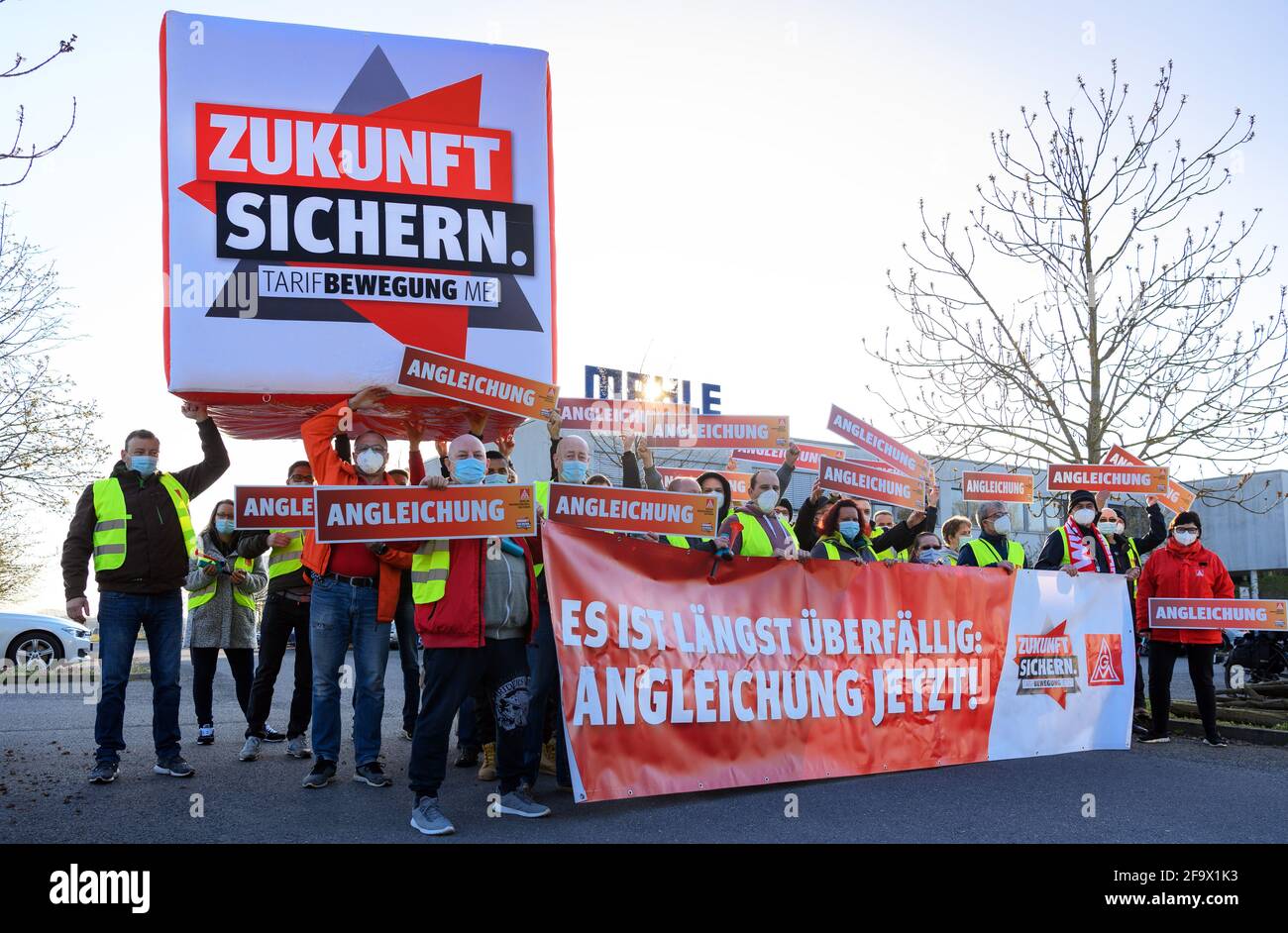 Wustermark, Allemagne. 21 avril 2021. Les employés du quart de travail de Mahle Filtersysteme GmbH et les représentants d'IG Metall se tiennent à l'entrée de l'entreprise ce matin lors d'une grève d'avertissement d'IG Metall avec la bannière "il est trop tard: L'ajustement maintenant! L'action, qui a duré plus de trois quarts, avait pour but, entre autres, de mettre l'accent sur les demandes d'augmentation de salaire et les futures conventions collectives. Credit: Soeren Stache/dpa-Zentralbild/ZB/dpa/Alay Live News Banque D'Images