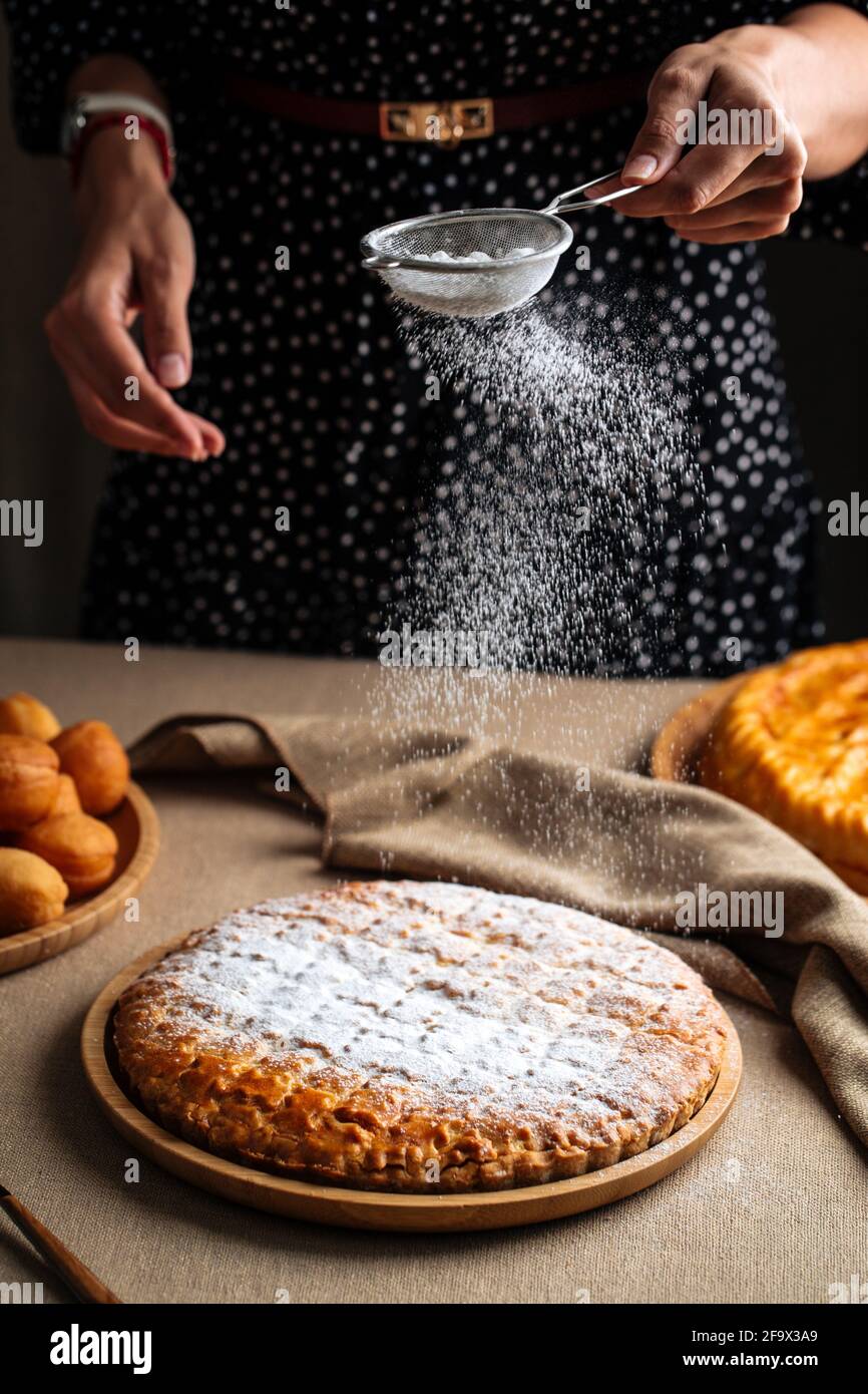 Saupoudrer la tarte fraîche avec du sucre en poudre Banque D'Images