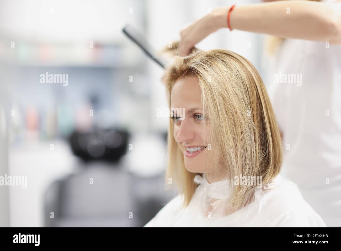 Coiffeur en train de réaliser une coupe de cheveux bob dans un salon de beauté Banque D'Images