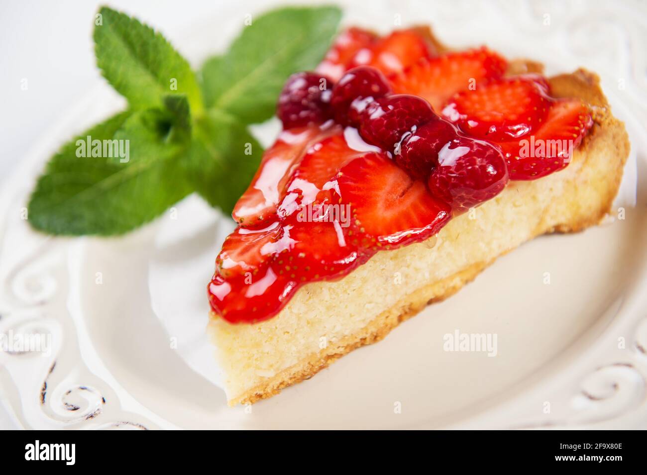 tranche de tarte aux fraises avec des fraises fraîches et une feuille de menthe sur une assiette de millésime, photo en gros plan Banque D'Images